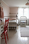 Old metal bed and floral wallpaper in vintage-style child's bedroom