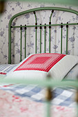 Handmade scatter cushions on green metal bed in bedroom