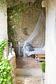 Metal bed with mosquito net on a Mediterranean covered terrace
