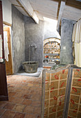 Old metal clawfoot tub in a nostalgic bathroom with terracotta tile floor