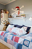 Skull and crossbones on wall above bed with patchwork quilt in child's bedroom