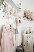 Romantic dresses and fabric dolls arranged on clothes rack