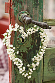 Heart-shaped wreath of lily-of-the-valley flowers hung from door handle