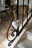 Fabric heart on an ornate metal banister on a stone staircase