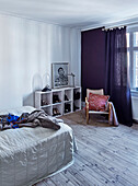 Bed, shelves and chair in bedroom with wooden floorboards