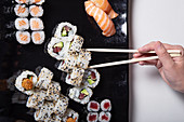 Person with chopsticks eating various sushi