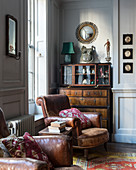 Brown leather armchair in front of antique cabinet in living room