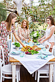 Frauen decken Tisch im sommerlichen Garten