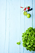 Grüner Blattsalat und Früchte auf hellblauer Holzfläche