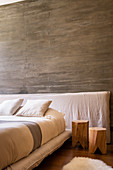 Wooden stool next to bed against board-formed concrete wall