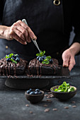 Pastry chef decorates brownie cake with blueberries and mint leaves