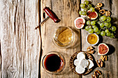 Glasses of red and white wine with grapes, figs, goat cheese and walnuts