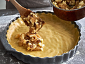 Vegan apple tart being made: filling being added to base