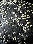 A black burger bun with sesame seeds (close-up)