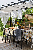 Dining table with chairs under pergola on terrace
