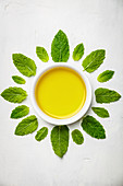 Olivenöl und Minzblätter auf weißem Hintergrund