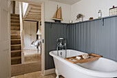 Freestanding bathtub against grey wainscoting in a country house