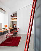 Red ladder on grey wall and desk in front of built-in cupboard