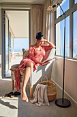 Woman relaxing and reading book in sunny window