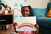 Portrait cute girl holding rainbow drawing