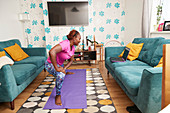 Woman practicing yoga online at laptop in living room