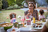 Mother enjoying summer barbecue with family on patio