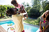 Happy family playing at sunny summer poolside