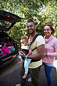 Portrait parents with toddler daughter outside car