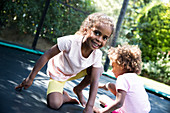 Portrait sisters playing on backyard trampoline