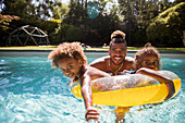 Portrait father and daughters playing in swimming pool