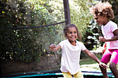 Happy sisters jumping on backyard trampoline