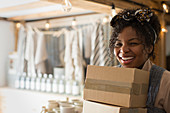 Portrait happy female shop owner carrying boxes