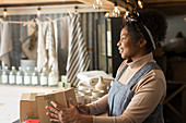 Happy female shop owner with boxes at shop counter