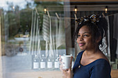 Thoughtful shop owner drinking coffee at shop window