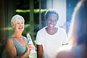 Happy senior women friends laughing on summer patio