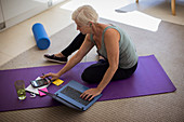 Senior woman paying bills and exercising at laptop