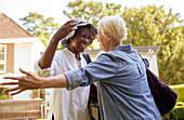 Senior women friends greeting and hugging in garden