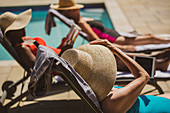 Senior women friends sunbathing at summer poolside