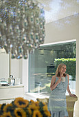 Senior woman drinking tea in dining room with chandelier