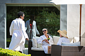 Senior women friends relaxing in spa robes on hotel patio