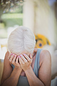 Stressed senior woman with head in hands