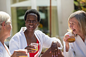 Happy senior women friends enjoying cocktails on patio