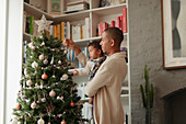Father and baby daughter decorating Christmas tree