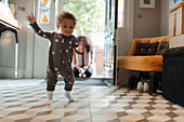 Cute baby girl in star pyjamas learning to walk at home