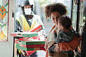 Mother and baby daughter receiving pizza delivery