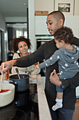 Couple with baby daughter cooking at kitchen stove