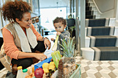 Mother watching baby girl eating celery