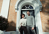 Portrait couple standing at front door on house stoop