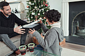 Wife opening Christmas gift from husband in living room