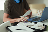 Man with receipts and calculator paying bills at laptop